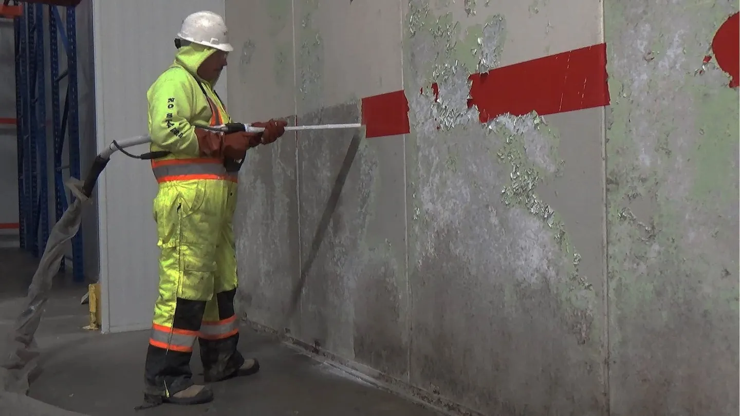 Technician dry ice blasting a painted concrete wall