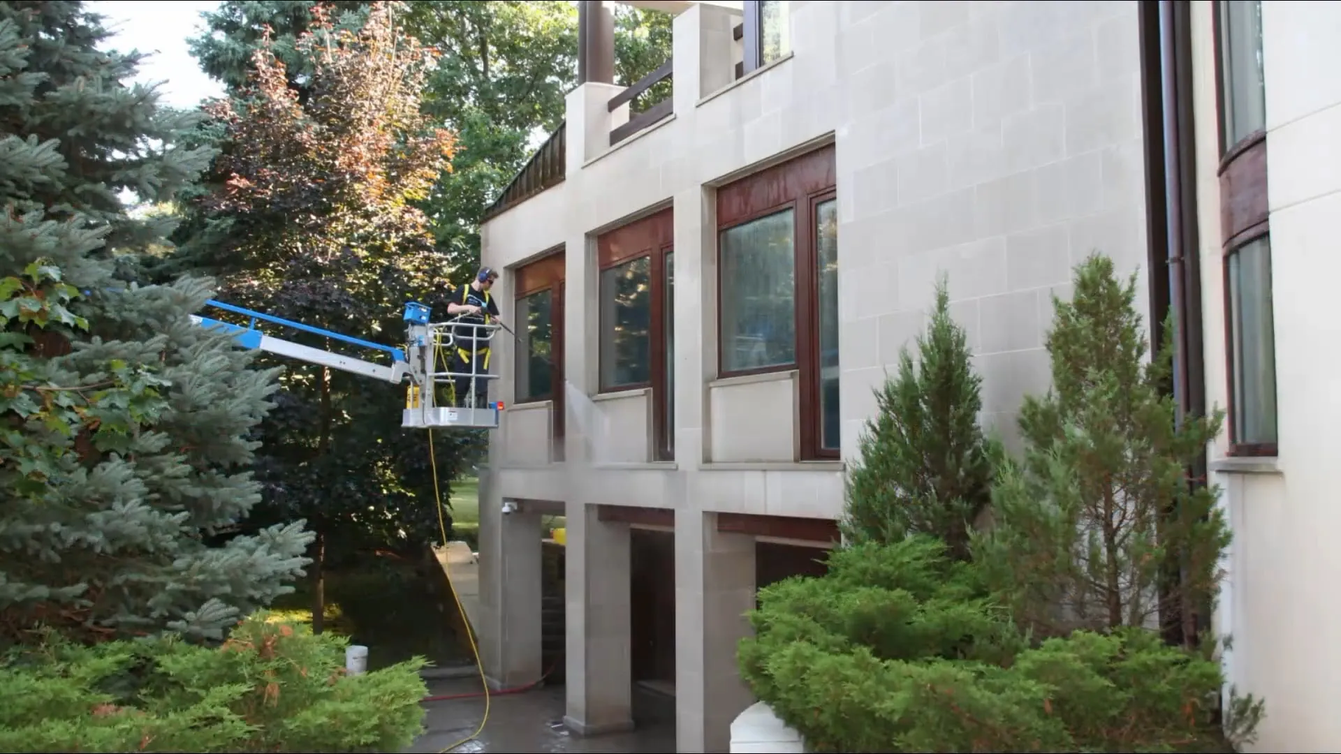 Revive crew washing a commercial building facade from a boom lift
